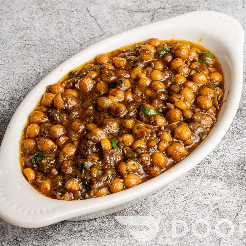A white oval dish filled with Aladdin Indian & Pakistani Restaurant's Chana Masala, a chickpea curry.