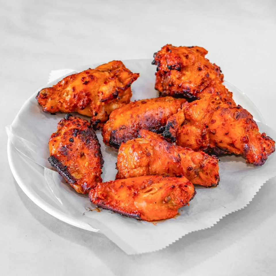 A white plate holds several pieces of Aladdin Indian & Pakistani Restaurant's spicy grilled chicken wings.